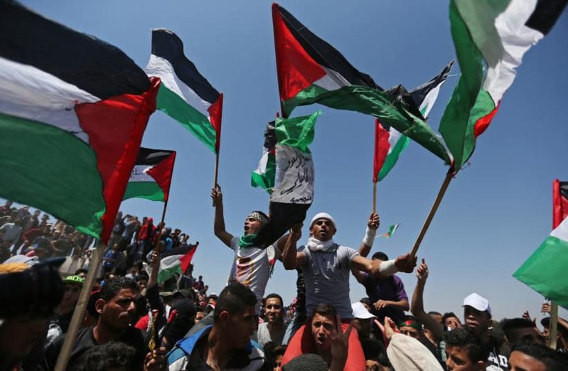 Demonstrators hold Palestinian flags during a protest marking the 71st anniversary of the 'Nakba', or catastrophe, when hundreds of thousands fled or were forced from their homes in the war surrounding Israel's independence in 1948, near the Israel-Gaza border fence, in the southern Gaza Strip May 1 (photo credit: IBRAHEEM ABU MUSTAFA / REUTERS)