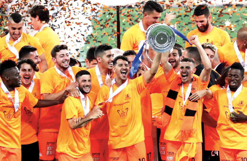 BNEI YEHUDA players lift the State Cup trophy following their impressive victory over Maccabi Netanya in Wednesday night’s State Cup final in Haifa. (photo credit: DANNY MARON)