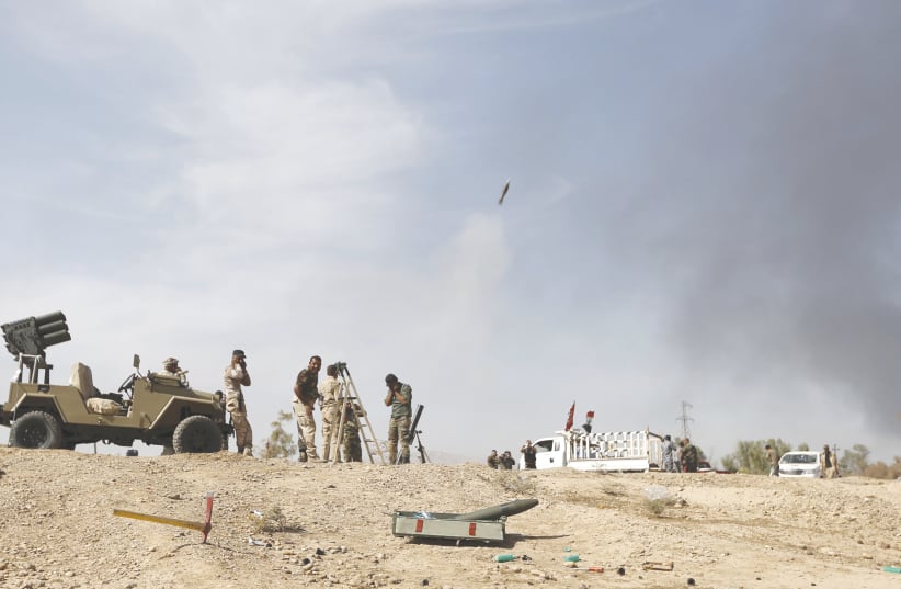 SHI’ITE FIGHTERS launch a mortar round toward Islamic State lines in al-Fatha, northeast of Baiji, in 2015. Iraqi forces, backed by Shi’ite militia fighters, say they have retaken a mountain palace complex of former president Saddam Hussein from Islamic State fighters, as government forces push ahea (photo credit: THAIER AL-SUDANI/REUTERS)
