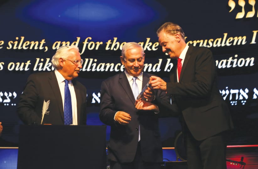 FRIENDS OF ZION founder Dr. Mike Evans presents a gift to Prime Minister Benjamin Netanyahu as US Ambassador to Israel David Friedman looks on last week at a ceremony marking the one-year anniversary to the moving of the US embassy to Jerusalem (photo credit: YOSSI ZAMIR)