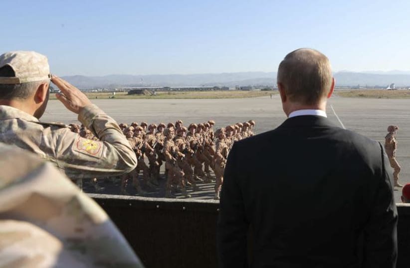Russian President Vladimir Putin (R) and Defence Minister Sergei Shoigu watch servicemen passing by as they visit the Hmeymim air base in Latakia Province, Syria (photo credit: REUTERS)