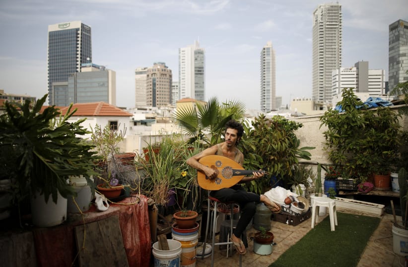 Musician Iyar Semel, 38, on his rooftop garden, where he grows herbs and vegetables, in Tel Aviv. Iyar planted an organic garden on his rooftop, with compost, vegetables, fruit trees and a shower, allowing him to merge his ecological lifestyle with the restraints of urban space. (photo credit: REUTERS/CORINNA KERN)
