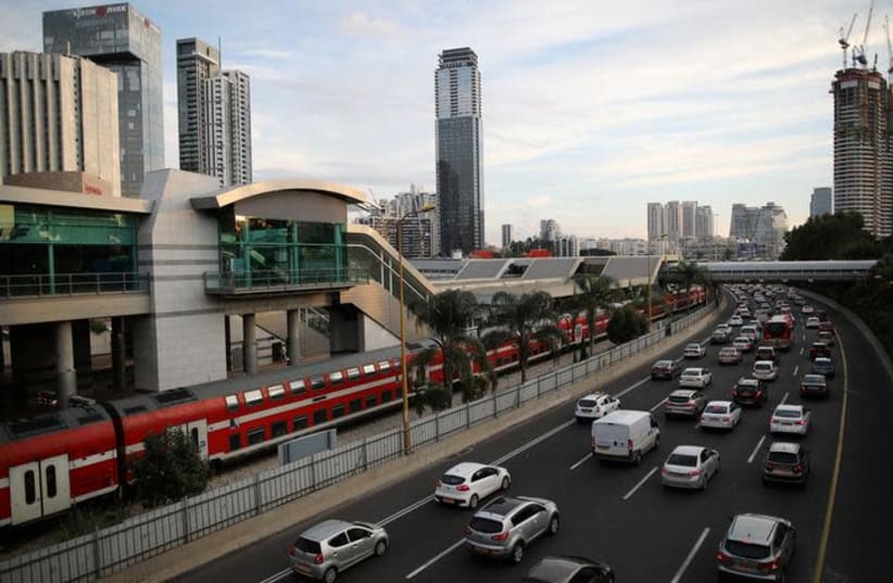 Cars drive on a highway as a train enters a station in Tel Aviv (photo credit: CORINNA KERN/REUTERS)