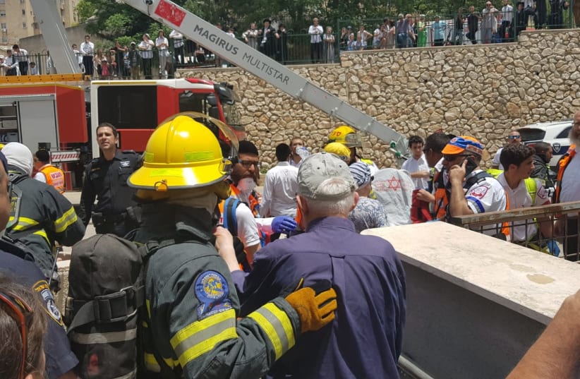 The fire and rescue forces in Tsfat help citizens out of their building which rose up in flames seemingly due to the extremely warm weather. (photo credit: ALON HACHMON)