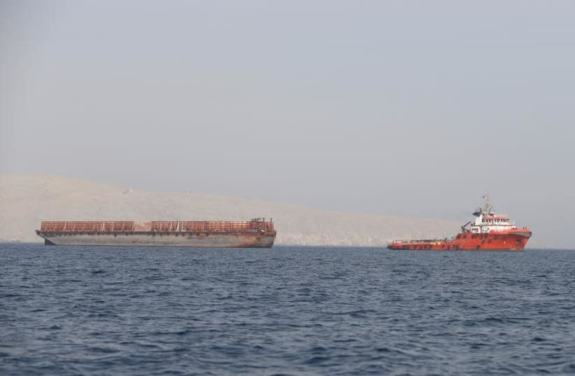 A tugboat moves cargo towards the Strait of Hormuz off the coast of Musandam province, Oman, July 20, 2018 (photo credit: HAMAD I MOHAMMED/REUTERS)