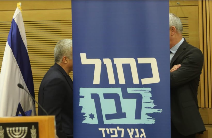 Blue and White leaders Benny Gantz (R) and Yair Lapid share words behind a party poster (photo credit: MARC ISRAEL SELLEM)