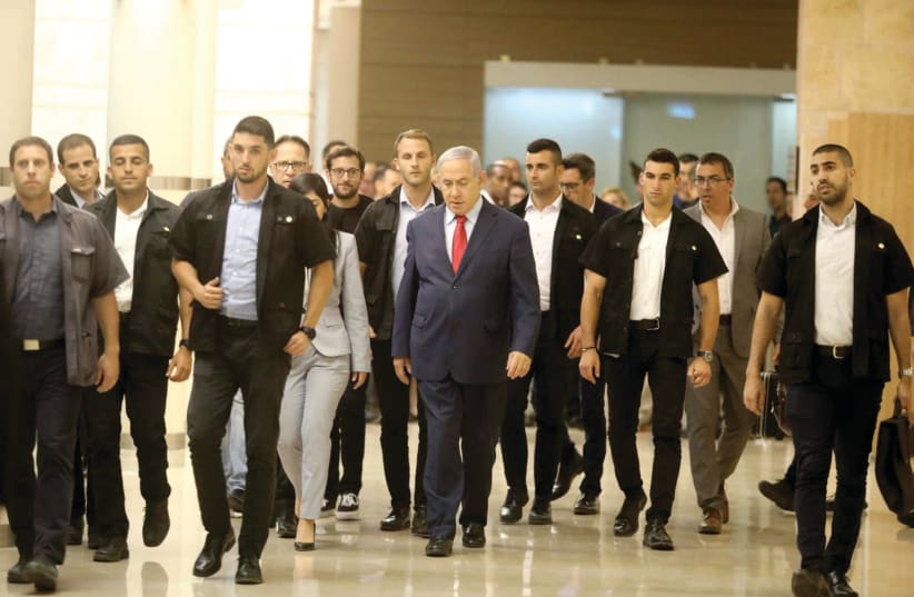 PRIME MINISTER Benjamin Netanyahu walks with his entourage in the Knesset on Wednesday night.  (photo credit: MARC ISRAEL SELLEM)