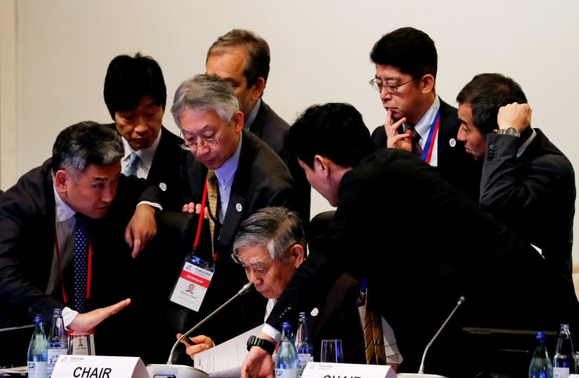 Haruhiko Kuroda, governor of the Bank of Japan (BOJ) is surrounded by his delegates during the G20 finance ministers and central bank governors meeting in Fukuoka, Japan June 8, 2019 (photo credit: REUTERS/KIM KYUNG-HOON/POOL)