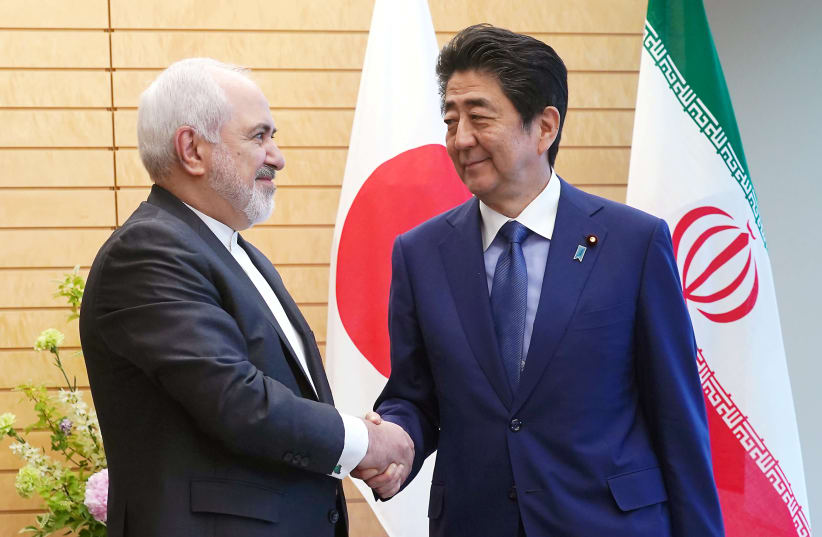  Iranian Foreign Minister Mohammad Javad Zarif, left, and Japanese Prime Minister Shinzo Abe, right, shake hands at Abe's official residence in Tokyo Thursday, May 16, 2019.  (photo credit: EUGENE HOSHIKO/POOL - REUTERS)