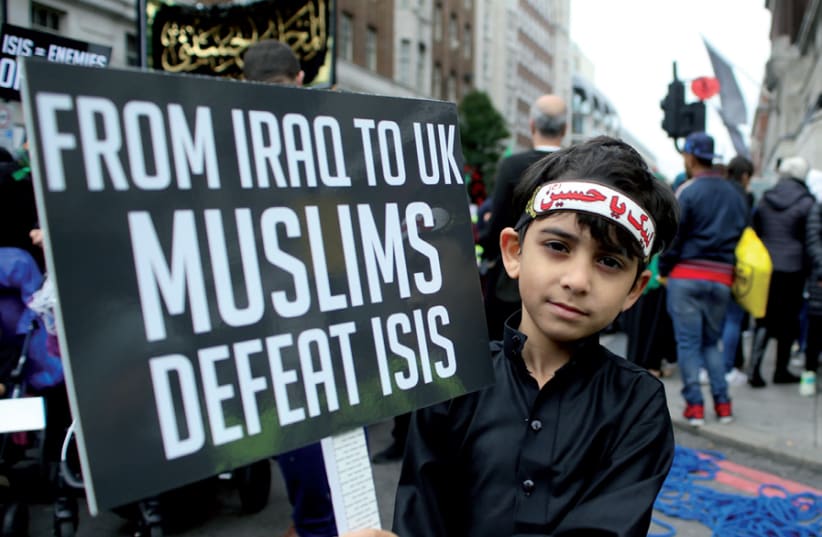 A boy holds a protest banner during an anti-ISIS march in central London (photo credit: TOM JACOBS/REUTERS)