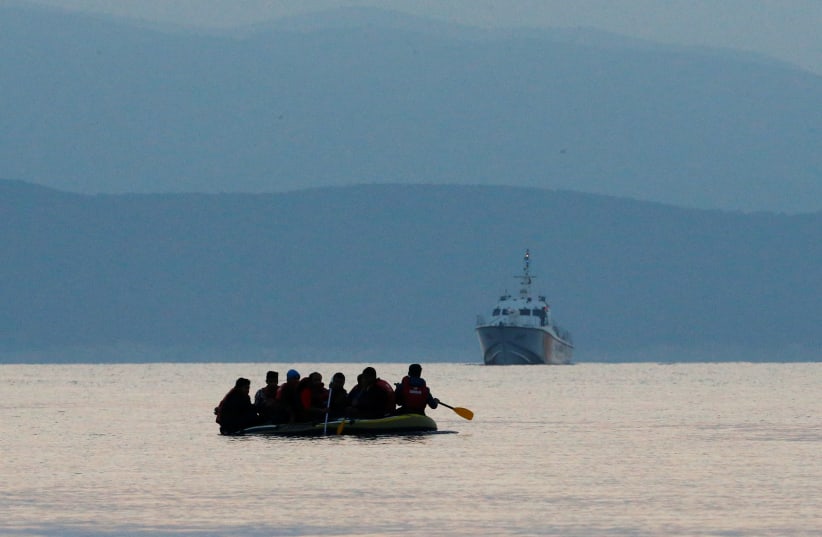 Migrants in a dinghy paddle their way on the Mediterranean Sea to attempt crossing to the Greek island of Kos, as a Turkish Coast Guard ship patrols off the shores off Bodrum, Turkey, September 19, 2015 (photo credit: UMIT BEKTAS / REUTERS)