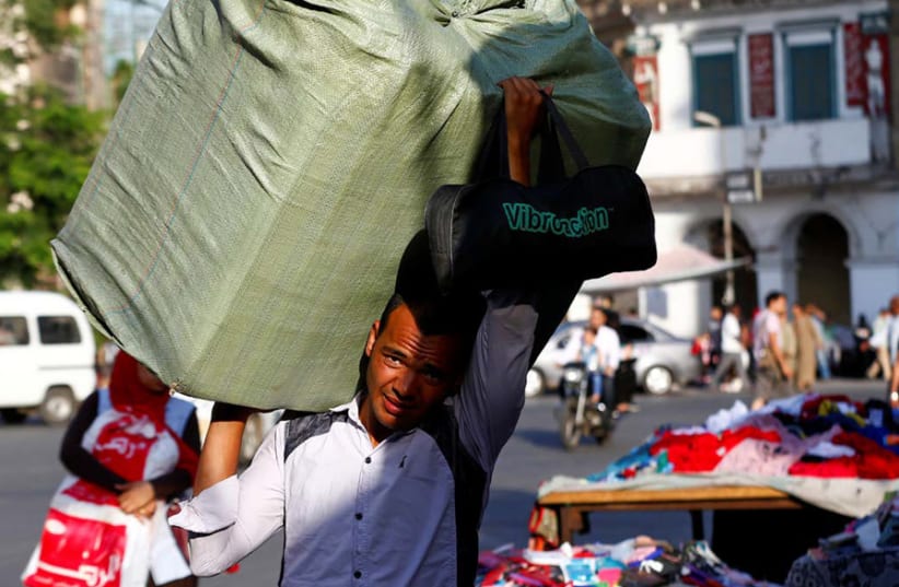 A WORKER carries goods for shops at Al Ataba, in Cairo on June 16. (photo credit: MOHAMED ABD EL GHANY/REUTERS)