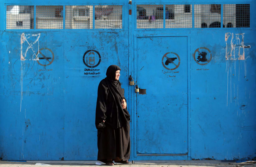 A Palestinian woman stands outside a closed school run by the United Nations Relief and Works Agency (UNRWA), during a strike by the agency's employees union to protest against job cuts, in Khan Younis in the southern Gaza Strip October 2, 2018 (photo credit: IBRAHEEM ABU MUSTAFA / REUTERS)