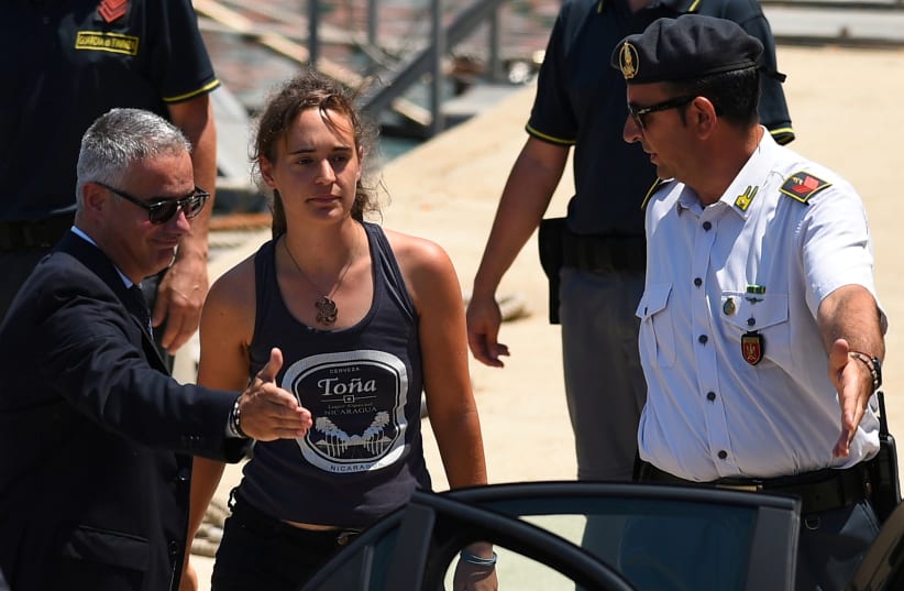 Carola Rackete, the 31-year-old Sea-Watch 3 captain, disembarks from a Finance police boat and is escorted to a car, in Porto Empedocle, Italy July 1, 2019 (photo credit: REUTERS/GUGLIELMO MANGIAPANE/FILE PHOTO)