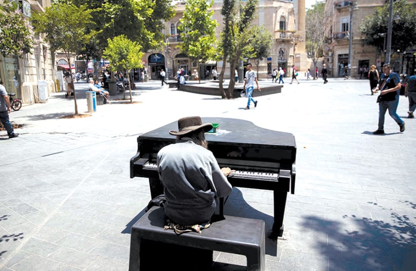 A HAREDI man plays a piano placed in Zion Square for the general public to play, in downtown Jerusalem on June 12. (photo credit: RONEN ZVULUN / REUTERS)