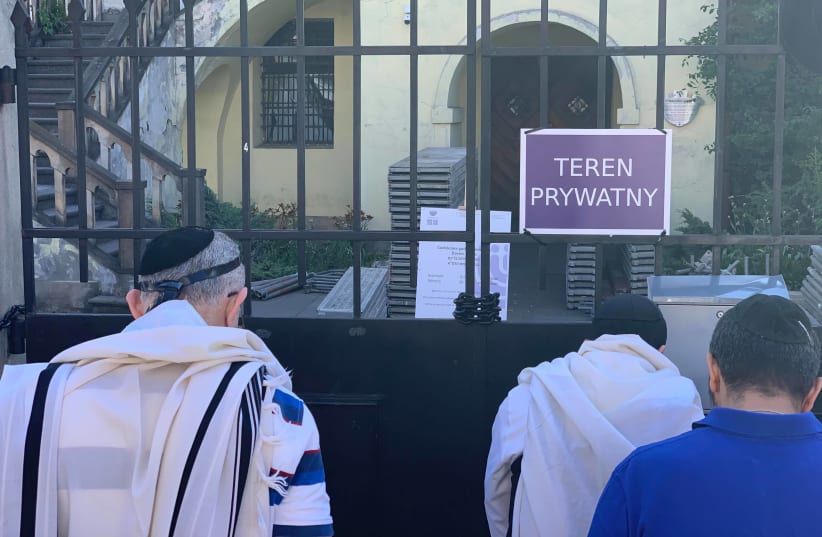 Jewish people in prayer outside Izaak Synagogue with a sign in front saying 'Private Property' '  (photo credit: Courtesy)