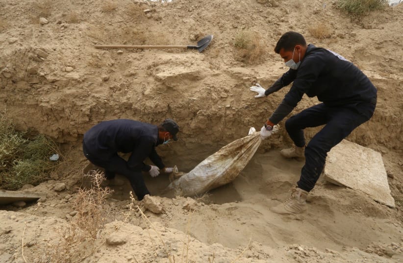 Workers pull an unidentified body at a mass grave in Raqqa, Syria October 16, 2018. Picture taken October 16, 2018. (photo credit: ABOUD HAMAM / REUTERS)