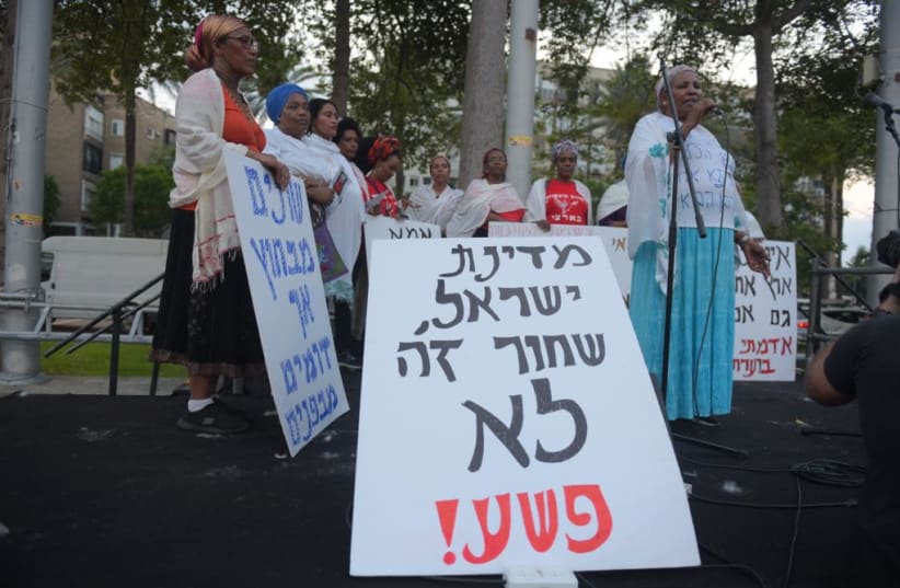 Protesters with a sign saying 'State of Israel, Being black is a crime'  (photo credit: AVSHALOM SASSONI)