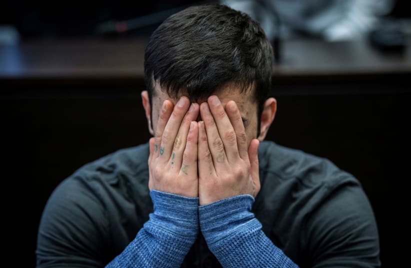 Ali Bashar covers his face during his trial for the murder and rape of Susanna Feldmann, March 2019. (photo credit: REUTERS)