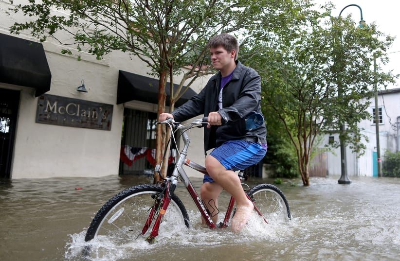 A resident bikes down a flooded street after Hurricane Barry in Mandeville (photo credit: JONATHAN BACHMAN/REUTERS)