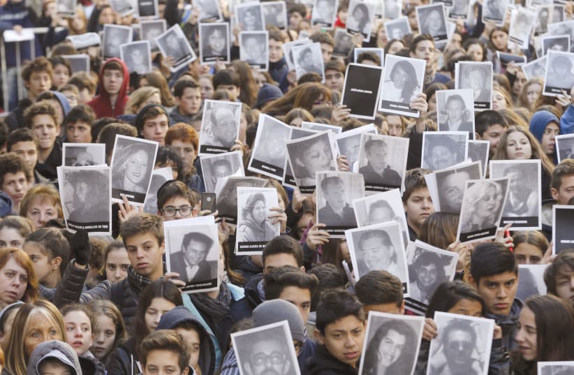 MEMBERS OF THE Argentinean Jewish community in Buenos Aires hold up pictures of the victims of the AMIA Jewish center bombing, during a ceremony in 2015 to mark the 21th anniversary of the 1994 attack (photo credit: ENRIQUE MARCARIAN / REUTERS)