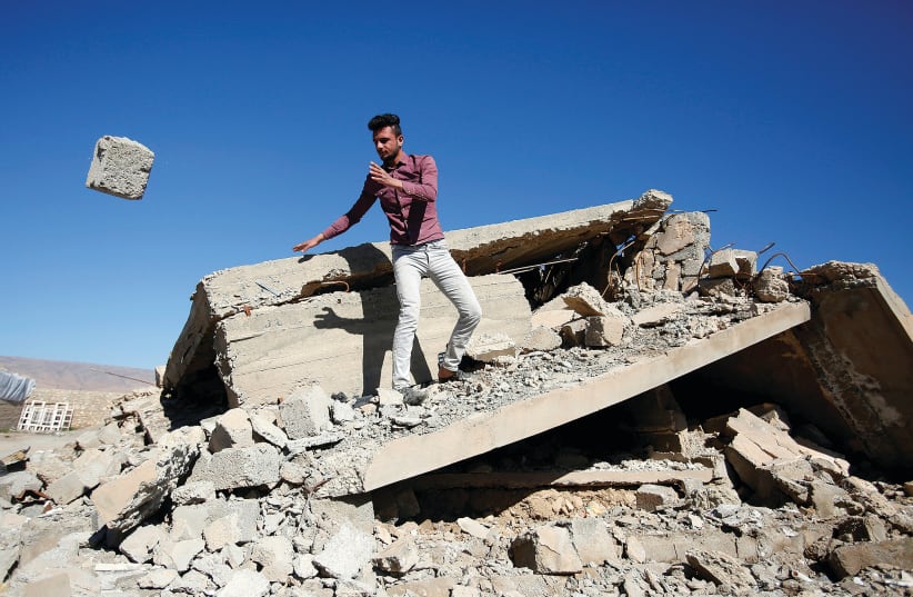 A YAZIDI man pulls rubble from his house in Sinjar that ISIS terrorists destroyed in February.  (photo credit: KHALID AL MOUSILY / REUTERS)