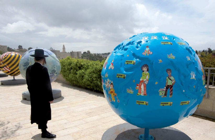 An ultra-Orthodox man observes the giant globes displayed outside the walls of Jerusalem’s Old City; the initiative of the non-profit organization Cool Globes aims to raise awareness of climate change (photo credit: RONEN ZVULUN)