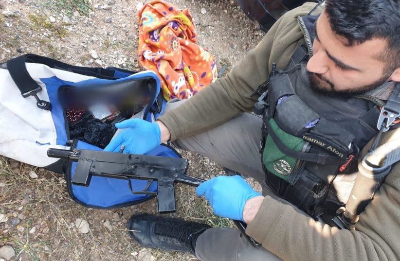 An Israel Police officer discovers an illegal firearm.  (photo credit: ISRAEL POLICE)