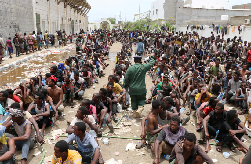 Ethiopian migrants, stranded in war-torn Yemen, sit on the ground of a detention site pending repatriation to their home country, in Aden, Yemen (photo credit: REUTERS)