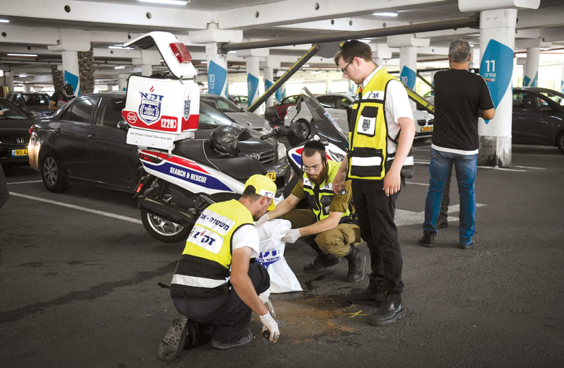 ZAKA MEDICAL personnel attend the scene where Ofir Hisdai was shot dead during an argument over a parking spot at the Azrieli Mall in Ramle on Sunday (photo credit: FLASH90)