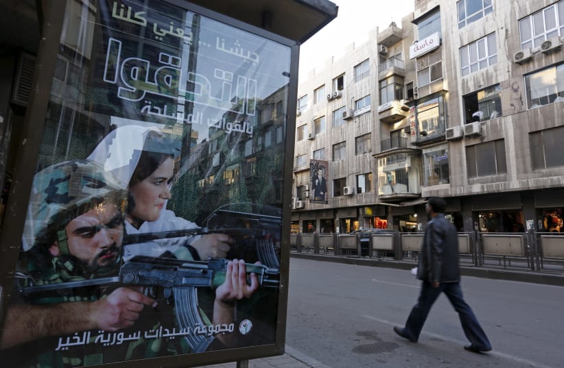 A man walks near an advertisement calling on people to join the Syrian military forces, in Damascus, Syria November 12, 2015. The text on the billboard reads in Arabic: "Our army means all of us, join the armed forces." (photo credit: OMAR SANADIKI/REUTERS)