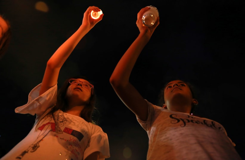 Mourners take part in a vigil near the border fence between Mexico and the U.S after a mass shooting at a Walmart store in El Paso U.S. in Ciudad Juarez (photo credit: REUTERS/CARLOS SANCHEZ)