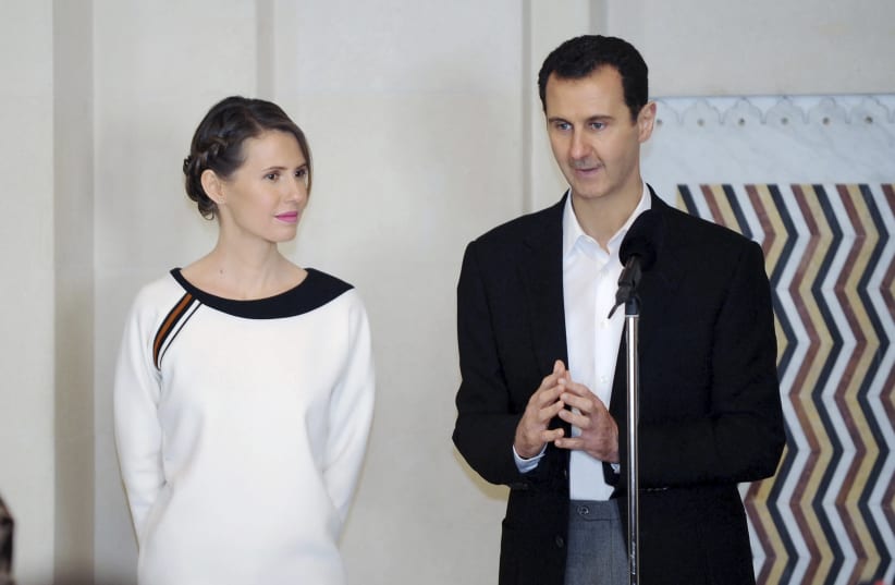 Syria's President Bashar al-Assad stands next to his wife Asma, as he addresses injured soldiers and their mothers during a celebration marking Syrian Mother's Day in Damascus in 2016 (photo credit: SANA/REUTERS)