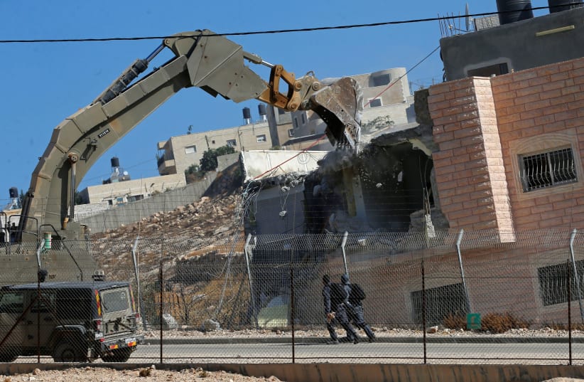 Israeli forces patrol as a machinery demolishes a Palestinian house in the village of Sur Baher which sits on either side of the Israeli barrier in East Jerusalem and the West Bank (photo credit: REUTERS/MUSSA QAWASMA)