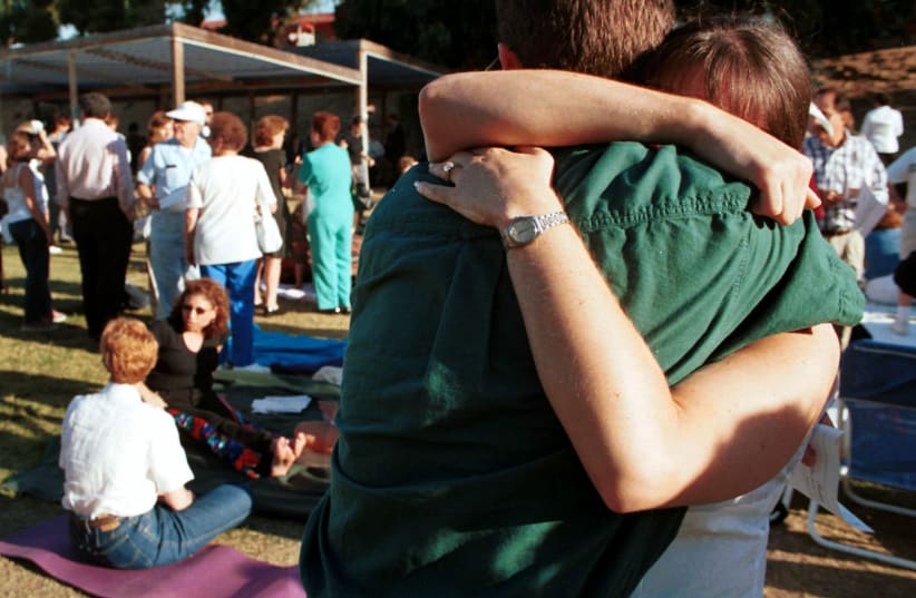 A couple embrace prior to a community gathering at the North Valley Jewish Community Center August 13, in the Granada Hills section of Los Angeles. The non-denominational service of "hope and healing" attracted approximately 350 people in the aftermath of the shooting at the center.  (photo credit: REUTERS)