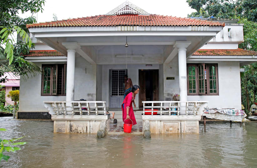 A woman clears out the water from her flooded house at Paravur on the outskirts of Kochi, in the southern state of Kerala, India August 11, 2019 (photo credit: REUTERS/SIVARAM V)