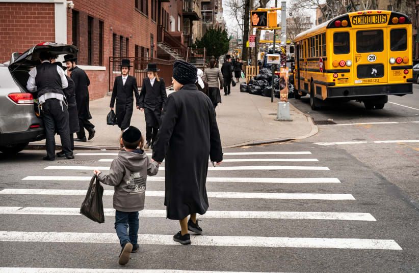Pedestrians walk past a yeshiva in the South Williamsburg neighborhood of Brooklyn, April 9, 2019. (photo credit: DREW ANGERER / GETTY IMAGES)