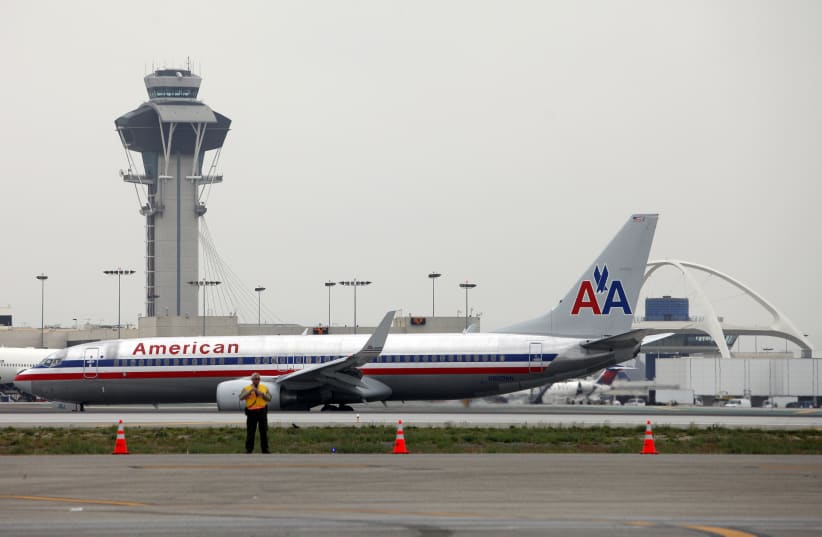 An American Airlines jet passes the Air Traffic Control Tower on the runway at Los Angeles International Airport (LAX), California April 24, 2013. Federal Aviation Administration (FAA) furloughs, which started Sunday, are intended to cut staffing by 10 percent to save $200 million of $637 million th (photo credit: REUTERS/PATRICK T. FALLON)