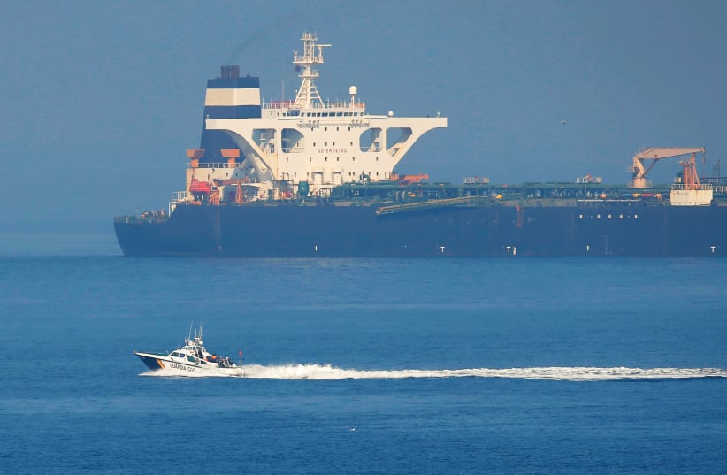 A Spanish Civil Guard boat sails past Iranian oil tanker Grace 1 as it sits anchored after it was seized in July by British Royal Marines off the coast of the British Mediterranean territory on suspicion of violating sanctions against Syria, in the Strait of Gibraltar, southern Spain August 13, 2019 (photo credit: JON NAZCA/ REUTERS)