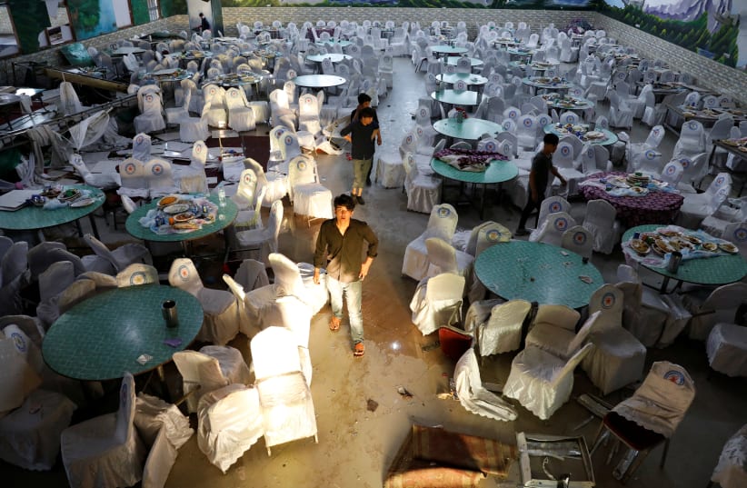Workers inspect a damaged wedding hall after a blast in Kabul, Afghanistan August 18, 2019 (photo credit: REUTERS/MOHAMMAD ISMAIL)