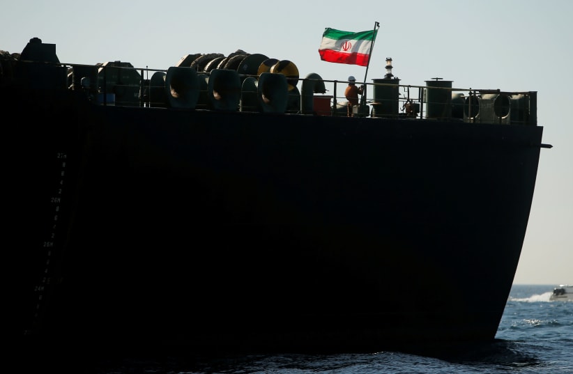 A crew member raises the Iranian flag on Iranian oil tanker Adrian Darya 1, previously named Grace 1, as it sits anchored after the Supreme Court of the British territory lifted its detention order, in the Strait of Gibraltar (photo credit: JON NAZCA/ REUTERS)