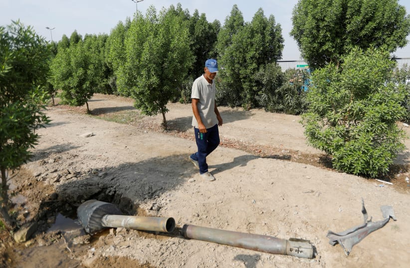  A man glances at a rocket that flew away from an Iraqi militia group's weapons depot after it caught fire, in Baghdad, Iraq, August 13, 2019 (photo credit: KHALID AL MOUSILY / REUTERS)