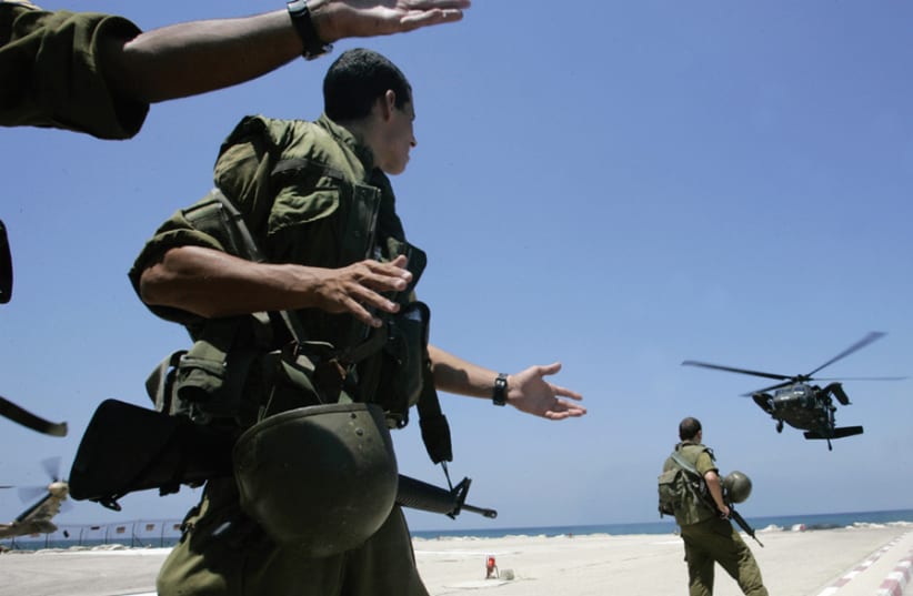 IDF soldiers watch as a helicopter carrying wounded soldiers lands at a hospital in Haifa, on July 26, 2006. (photo credit: ELIANA APONTE/REUTERS)