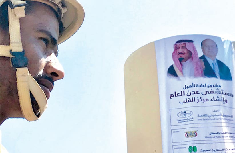 A YEMENI soldier eyes a poster portraying Saudi Arabia’s King Salman bin Abdulaziz Al Saud and Yemen’s President Abdrabbuh Mansur Hadi outside a hospital renovated by Saudi Arabia in Aden, Yemen, last December. (photo credit: NAEL SHYOUKHI/REUTERS)