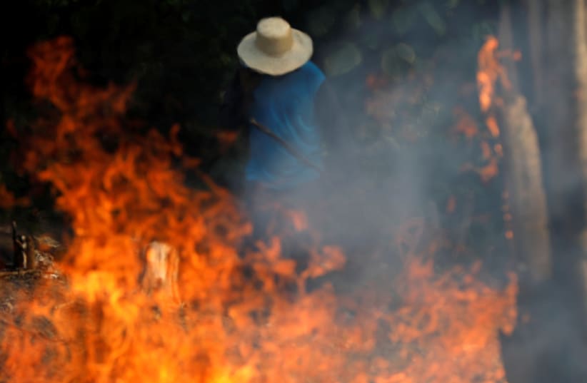 A man works in a burning tract of Amazon jungle as it is being cleared by loggers and farmers in Iranduba (photo credit: BRUNO KELLY/REUTERS)