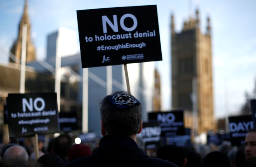 Protesters hold placards and flags during a demonstration, organised by the British Board of Jewish Deputies for those who oppose antisemitism, in Parliament Square in London (photo credit: HENRY NICHOLLS/REUTERS)