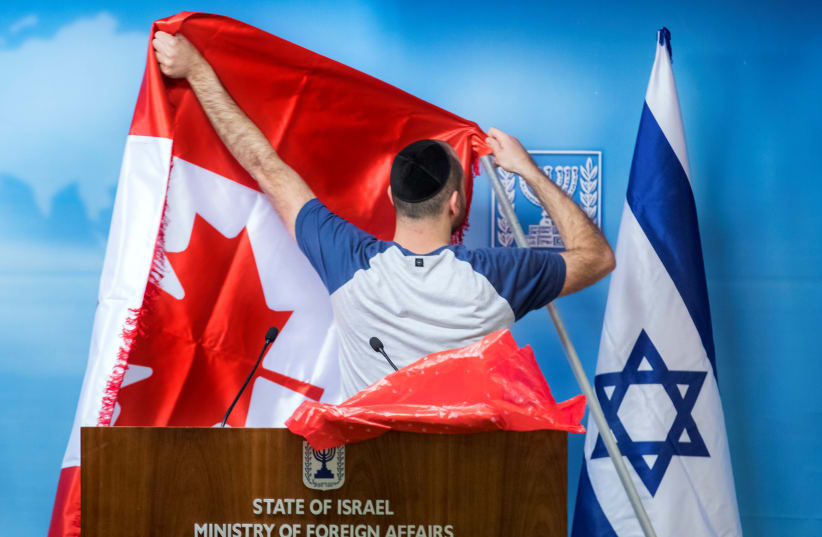 An employee adjusts the Canadian flag next to the Israeli one (photo credit: REUTERS)