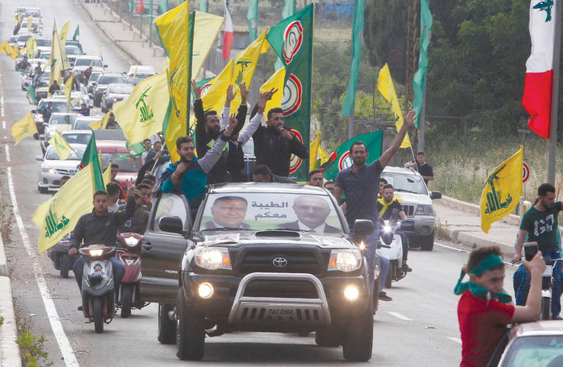 Supporters of Lebanon's Hezbollah and Amal movement gesture as they ride in a car in Marjayoun  (photo credit: REUTERS)