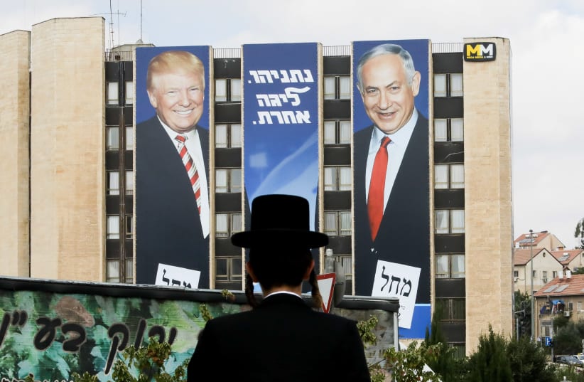 A haredi man stares at a Likud ad with Prime Minister Benjamin Netanyahu and US President Donald Trump. (photo credit: MARC ISRAEL SELLEM)