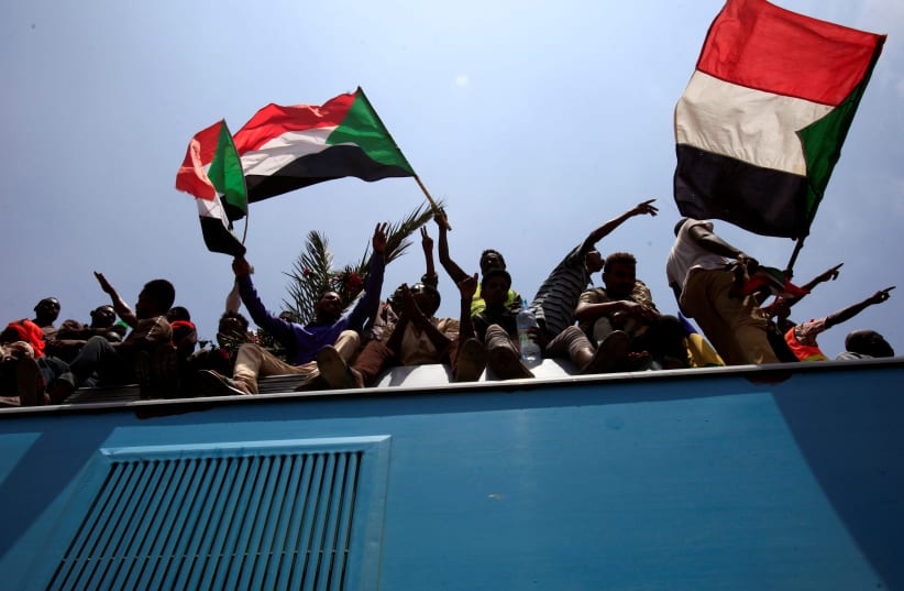 Sudanese civilians wave their national flags during the signing of the Sudan's power sharing deal, Khartoum (photo credit: REUTERS/MOHAMED NURELDIN ABDALLAH)